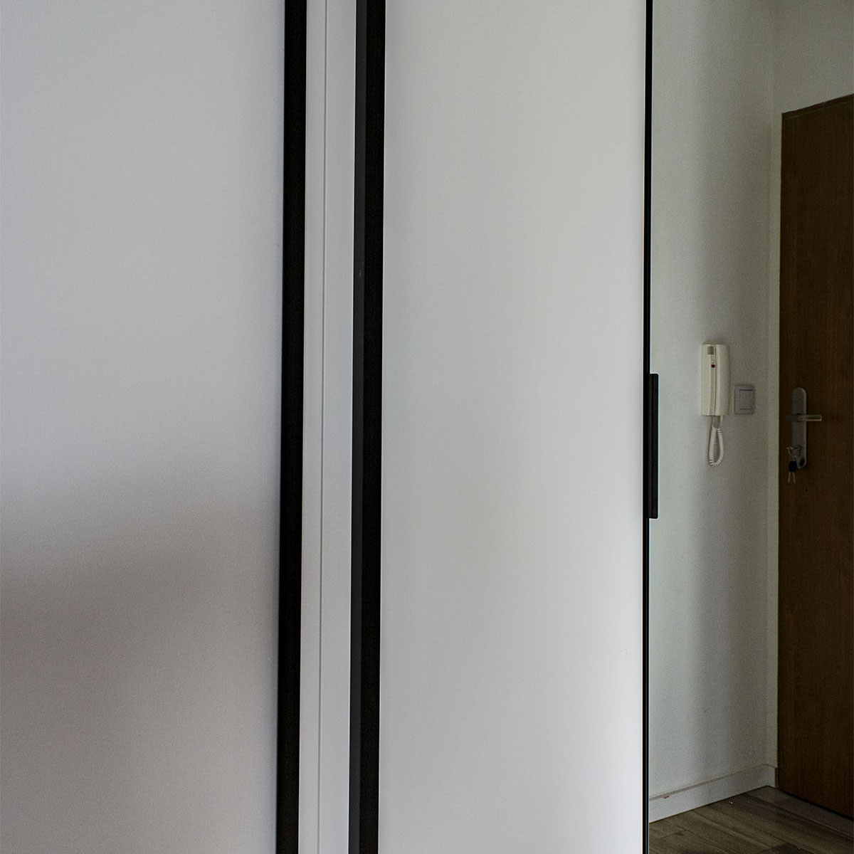 Biała szafa w przedpokoju z lustrem i czarnymi uchwytami - zdjęcie 9